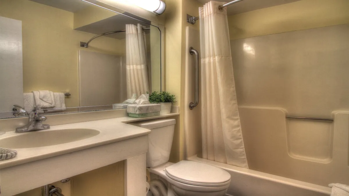 A modern bathroom with a clean vanity, sink, mirror, toilet, shower, and neatly folded towel. The space exudes a calm, refreshing vibe ideal for personal care and relaxation.
