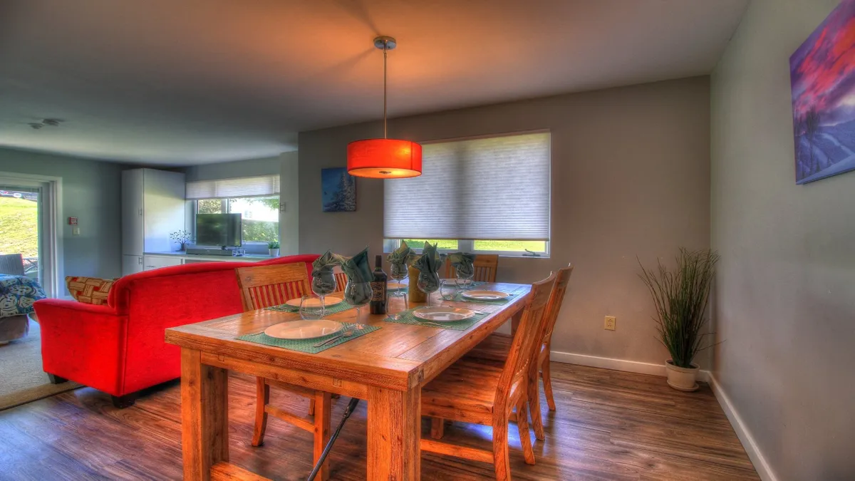This image showcases a dining area with a central table, red sofa, and hanging light fixture. The space is arranged to foster family meals, entertaining guests, and casual gatherings, exuding a warm, welcoming vibe. The decor and furniture suggest a comfortable, well-appointed suite ideal for relaxing after a day of adventure.
