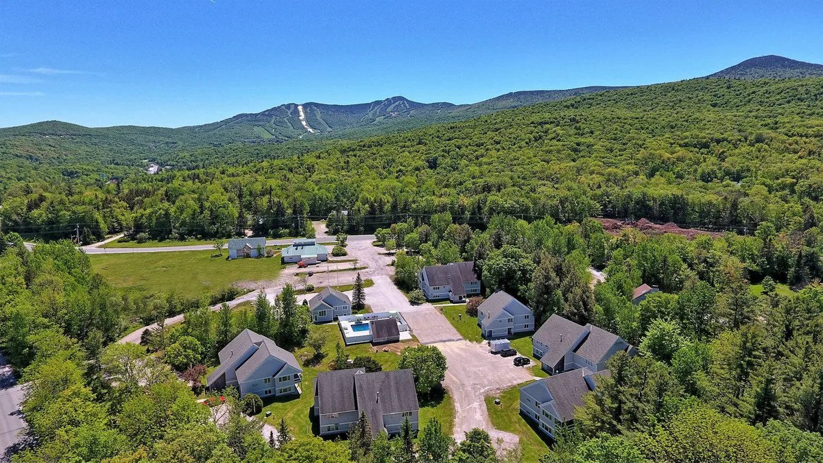A serene view of the mountains and surrounding greenery, with the Suites at Killington’s pool and buildings in the foreground. The landscape puts the resort in direct dialogue with the natural environment, emphasizing its tranquil yet accessible position.