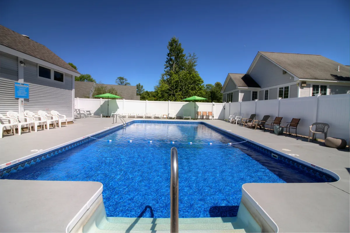 An inviting heated saltwater pool is surrounded by lounge chairs and green umbrellas, offering a relaxing and social outdoor environment. The warm lighting suggests a tranquil evening, perfect for unwinding after a day of adventure.