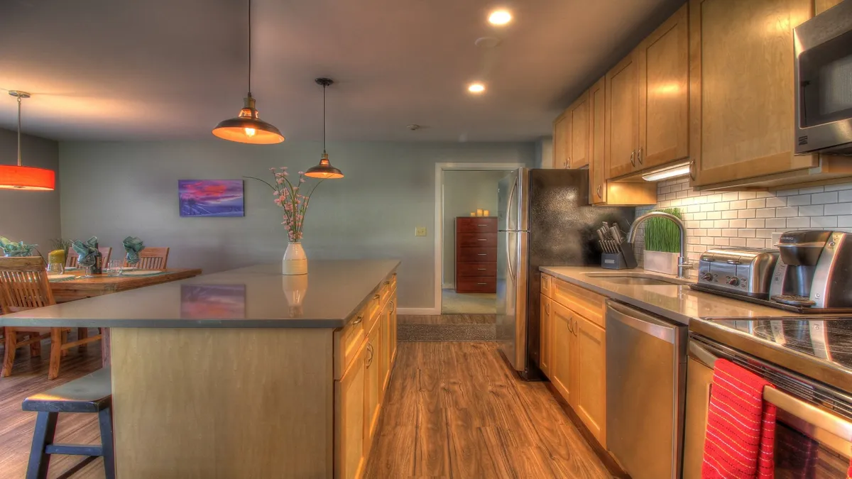 A spacious kitchen and dining area featuring a kitchen island, dining table, modern appliances, and a decorative vase. The layout allows for both socializing and preparing group meals, reinforcing the suite’s suitability for families and small groups.